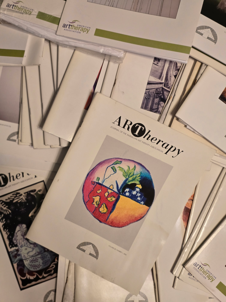Stack of art therapy journals featuring a colorful cover illustration of plants and flowers, highlighting the relevance of art in therapeutic practices.
