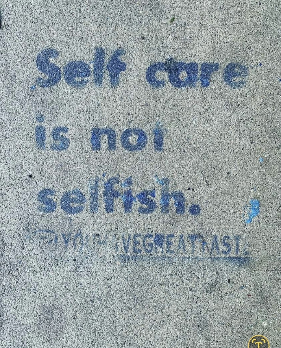 "Concrete message reads 'Self care is not selfish.' emphasizing the importance of self-care in public spaces."